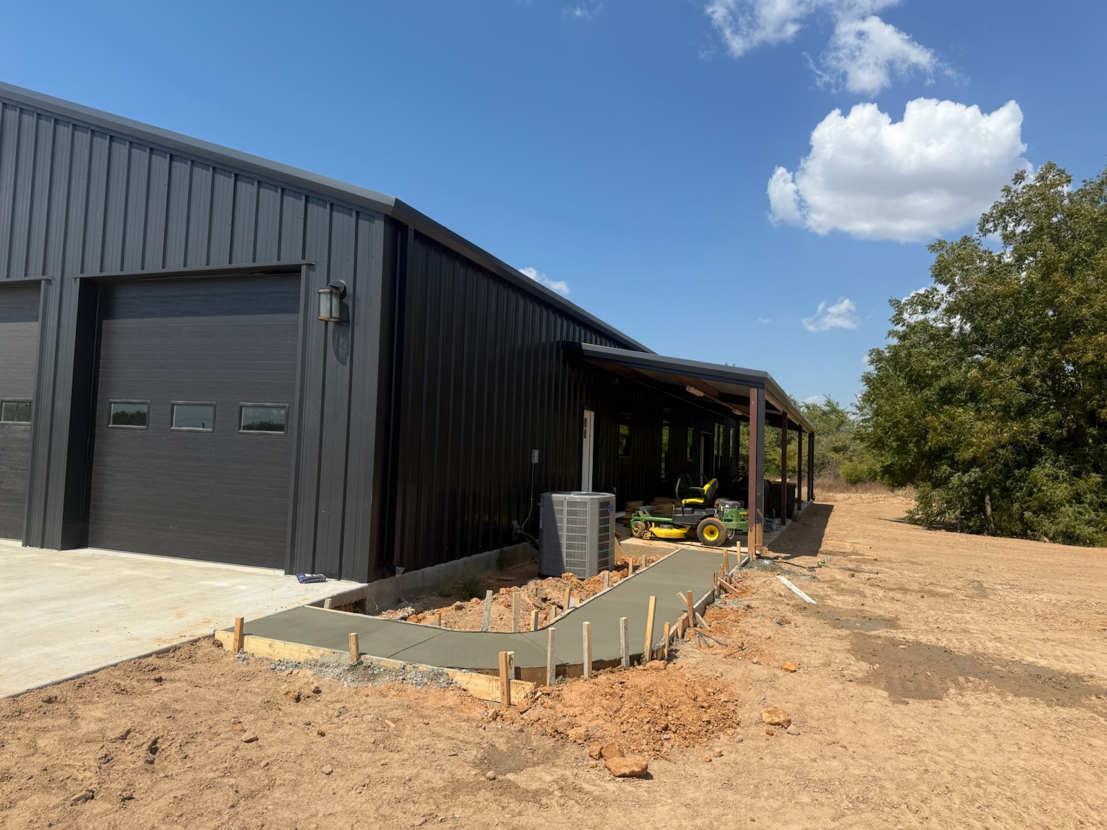 Curved concrete walkway beside a black metal building