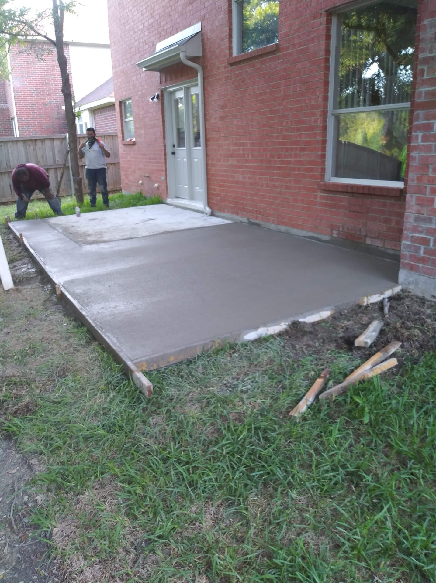 Fresh concrete patio and entry beside a brick home